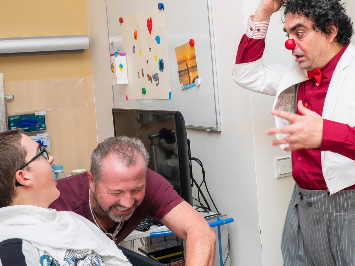 ROTE NASEN-Humorbotschafter Rolando Villazon in einem Krankenzimmer mit zwei Personen.