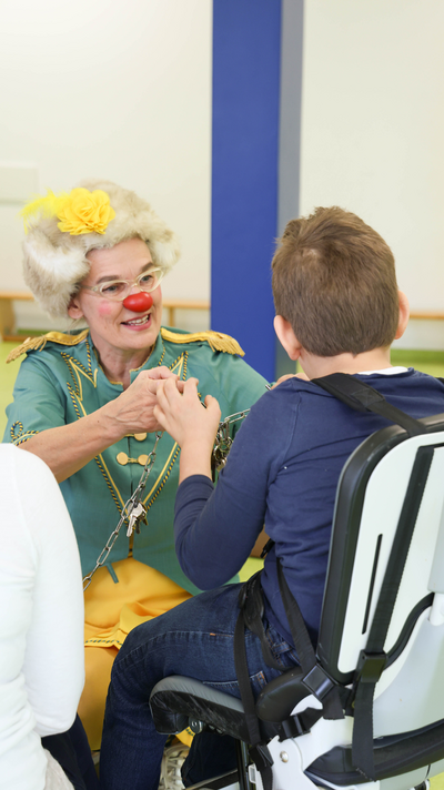 ROTE NASEN-Clownin Zitronella und ein Kind im Rollstuhl.