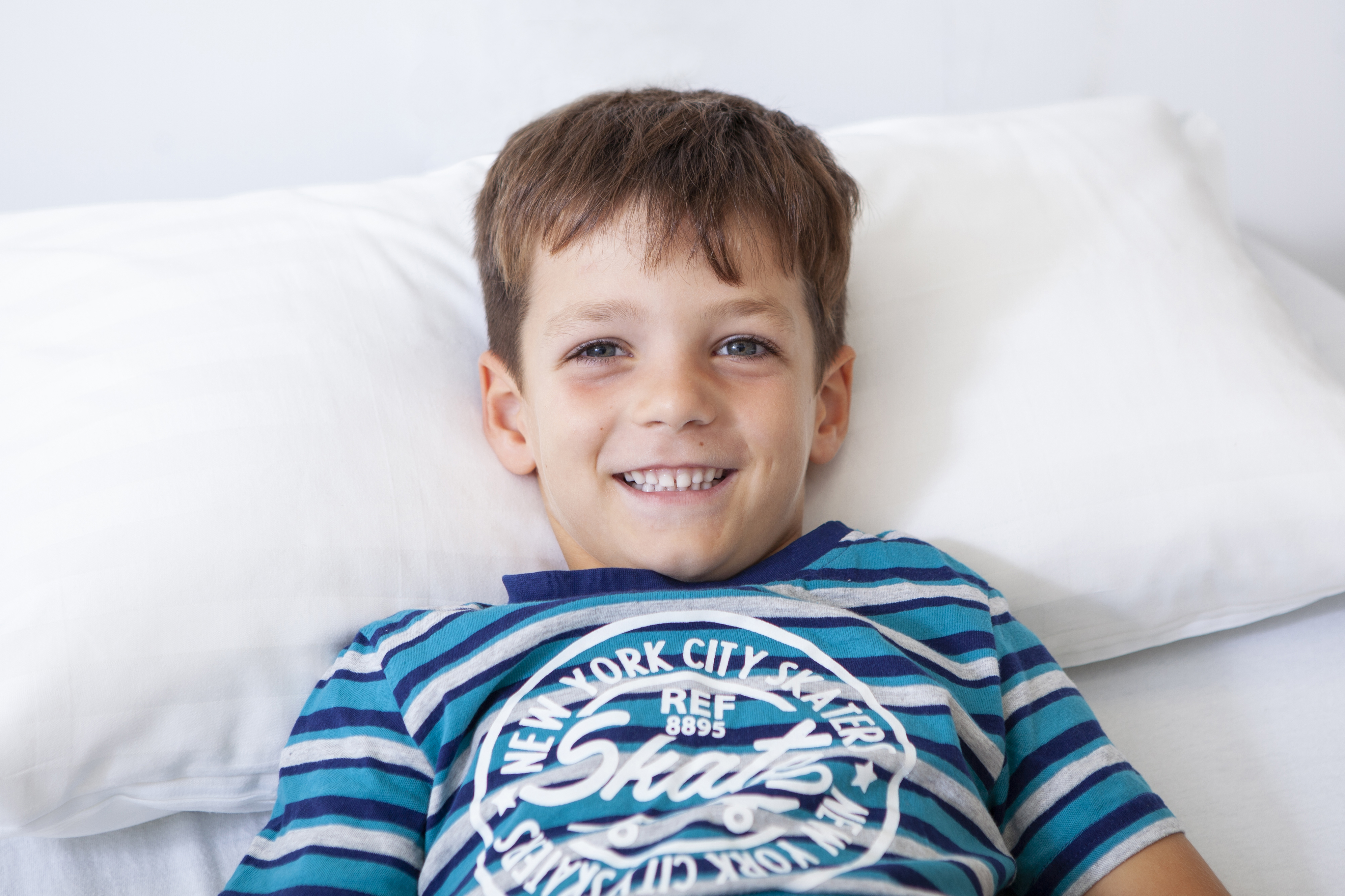 Profilbild eines Jungen, der in einem Bett liegt und ein blau-weiß gestreiftes T-Shirt trägt.